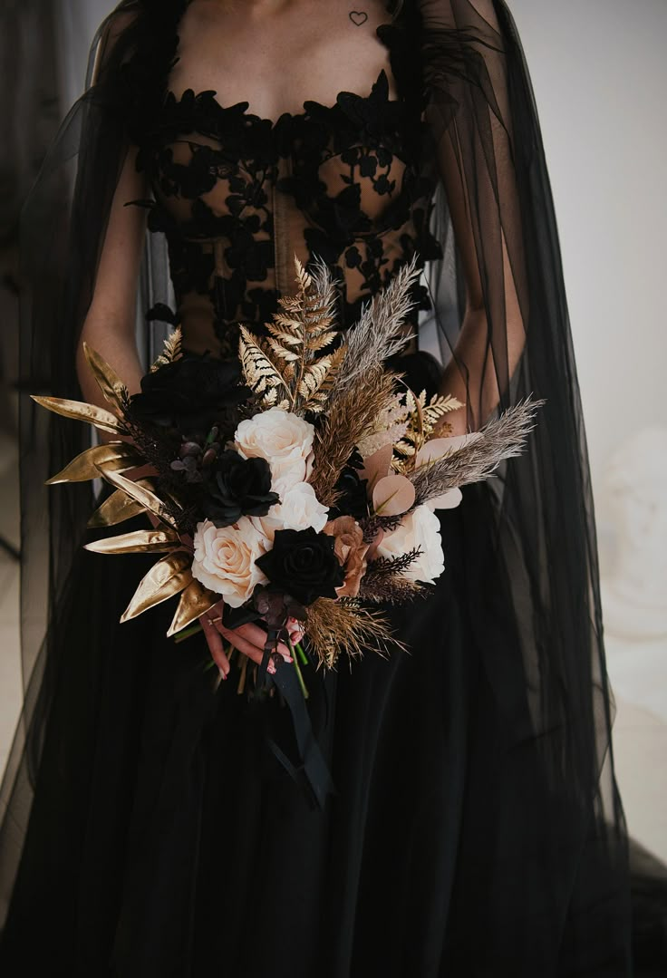 a woman in a black dress holding a bouquet with feathers on it's back