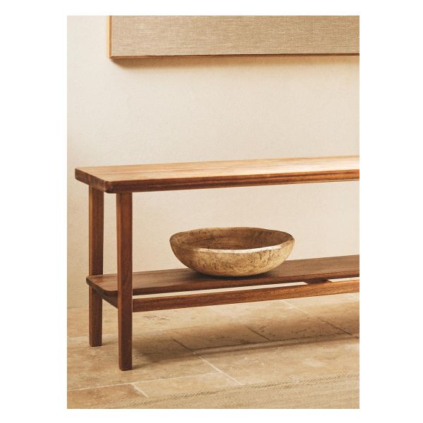 a bowl sitting on top of a wooden table next to a wall mounted art piece