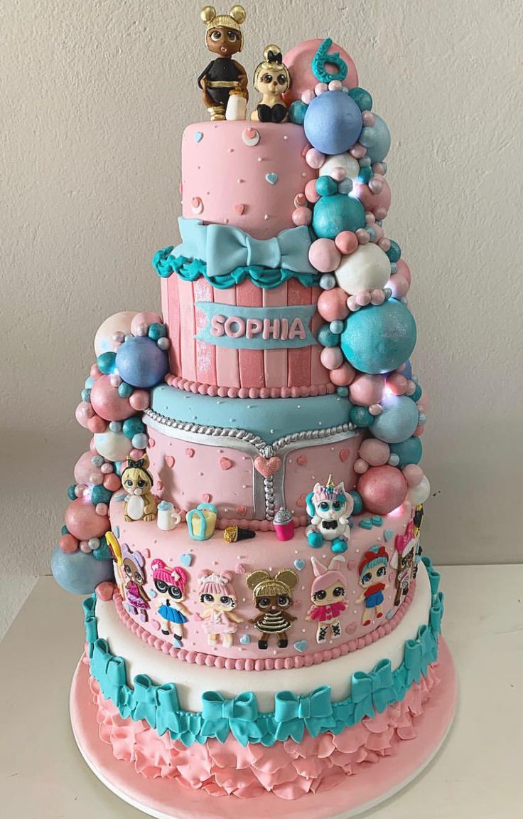 a three tiered cake decorated in pink, blue and white with animals on top