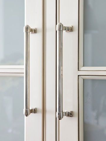 a close up view of the handles on a white cabinet with frosted glass doors