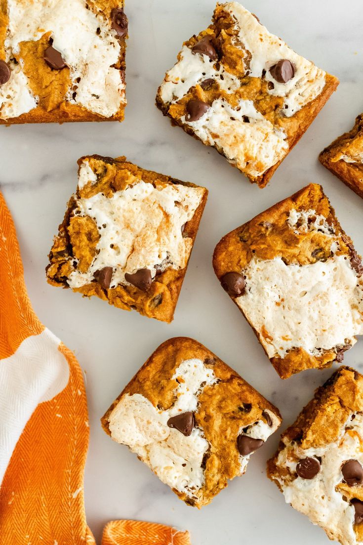 several pieces of dessert sitting on top of a white counter next to an orange napkin