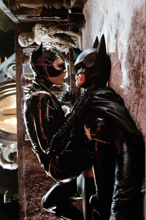 two people dressed as batman and catwoman sitting next to each other in a room