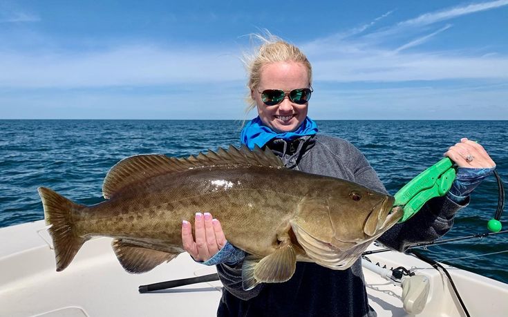 a woman on a boat holding a large fish