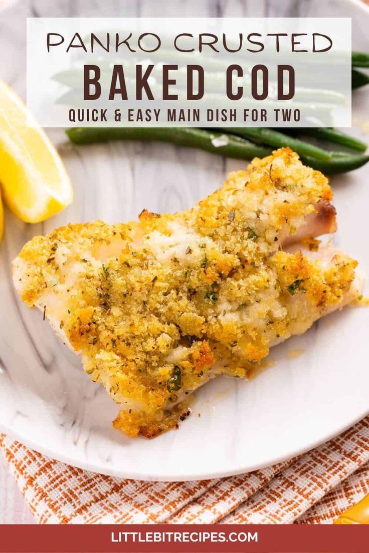 baked parmesan breaded chicken on a white plate with lemons and green beans