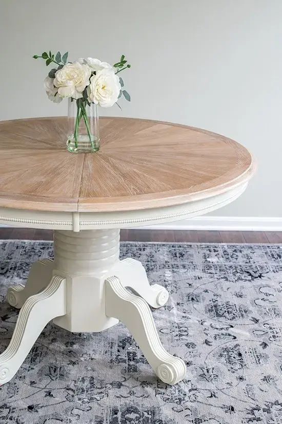 a round table with white flowers in a vase sitting on top of an area rug