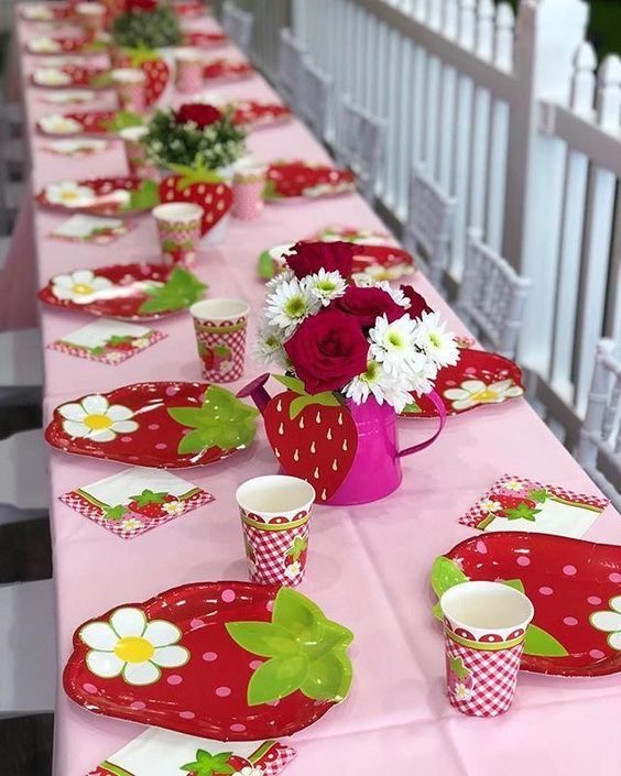 the table is set with red and white polka dot plates, cups, and vases