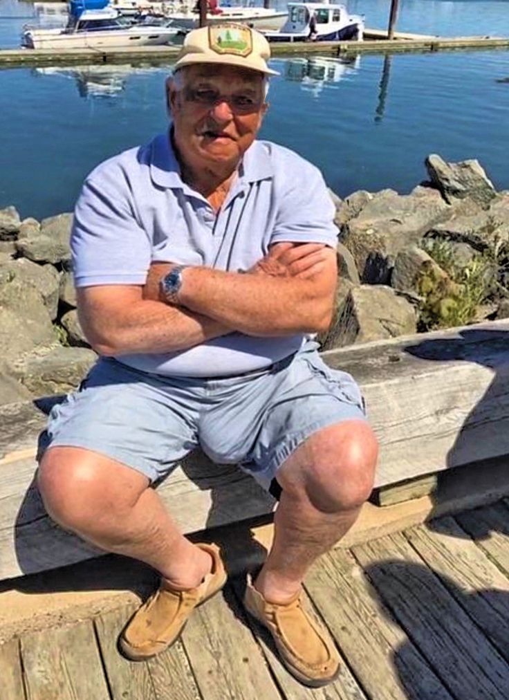 an older man sitting on a dock with his arms crossed