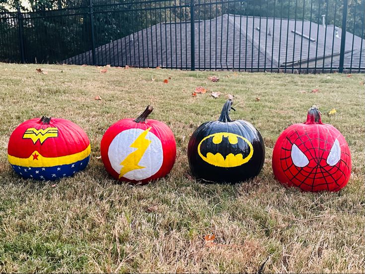 three pumpkins painted to look like batman, spiderman, and wonderworld characters