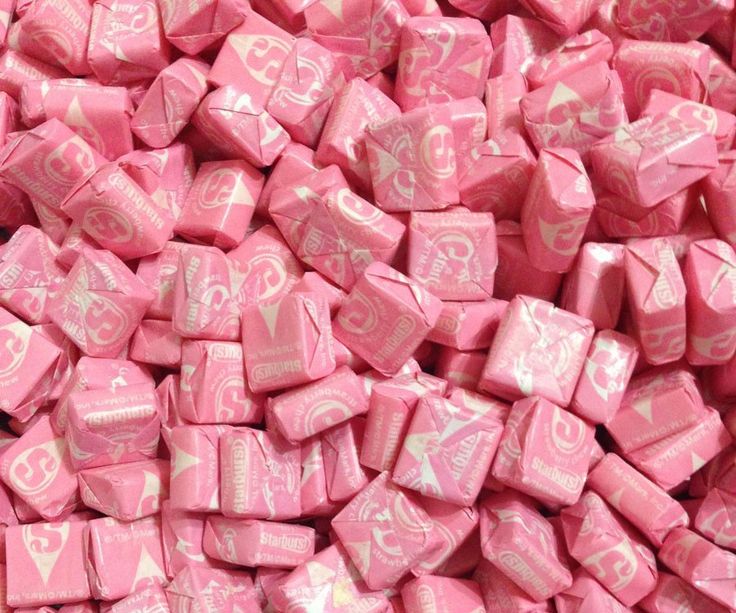 a pile of pink candy with white letters on it's sides and hearts in the middle