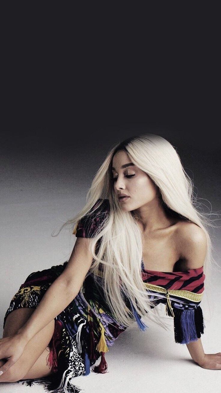 a woman with long white hair is sitting on the floor and posing for a photo