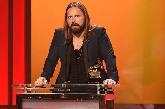 a man with long hair and beard standing at a podium in front of an award