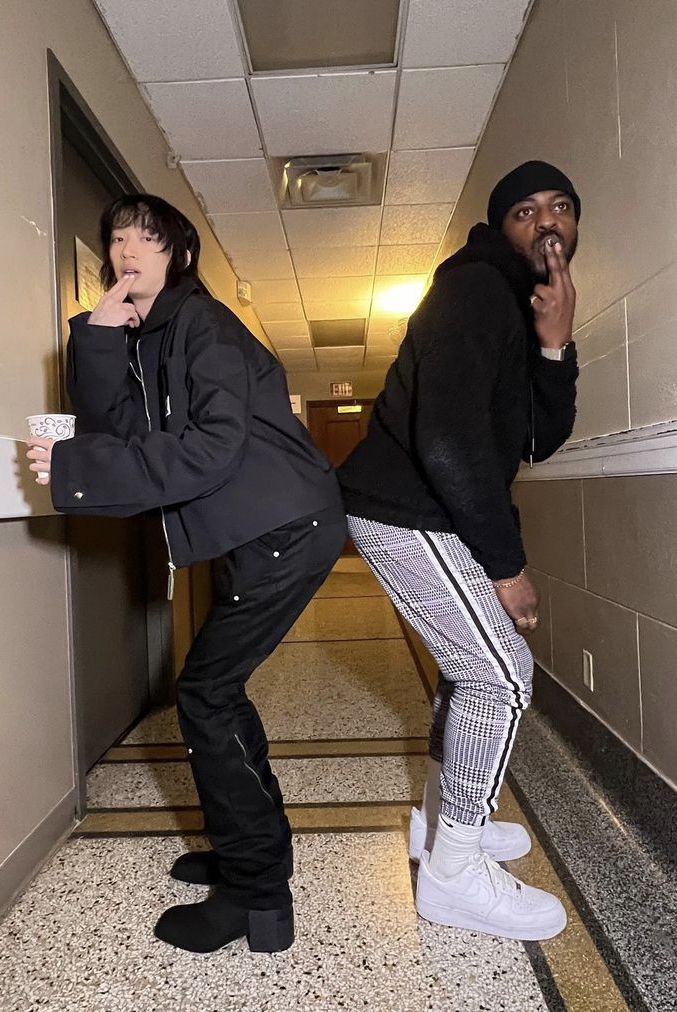 two men standing in an elevator one is holding a cup and the other has his mouth open