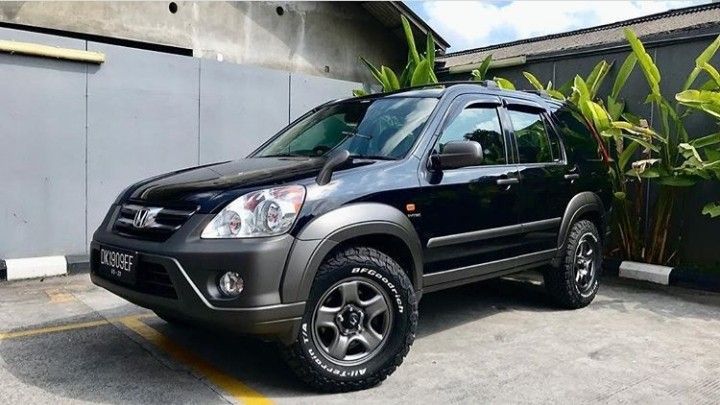 a black suv parked in front of a building with plants growing out of the back