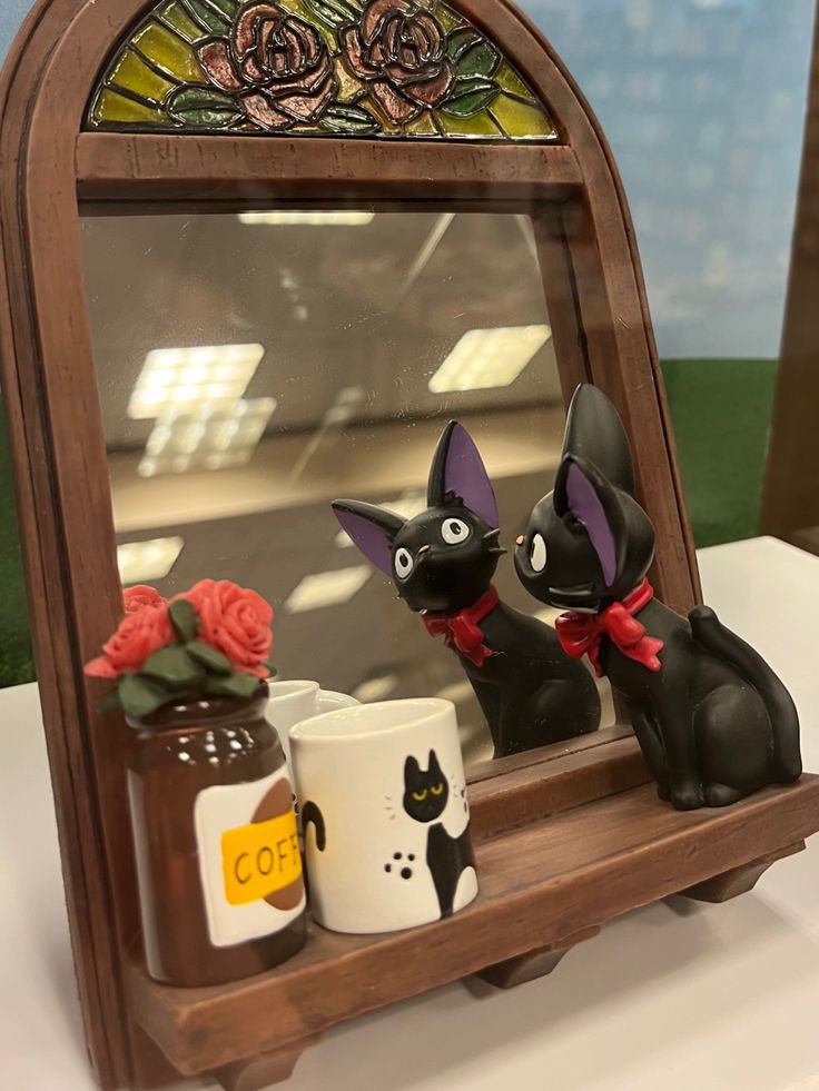 a mirror with two cats on it and some coffee mugs in front of it