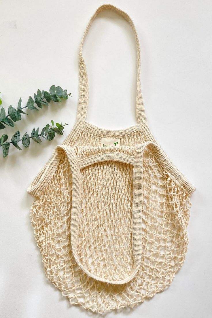 a crocheted bag sitting on top of a white table next to a plant