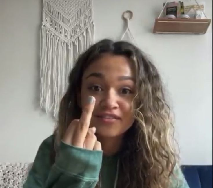 a woman with long curly hair is holding her finger up