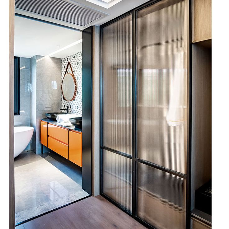 a bathroom with an orange cabinet and white bathtub in the background, along with a large mirror on the wall