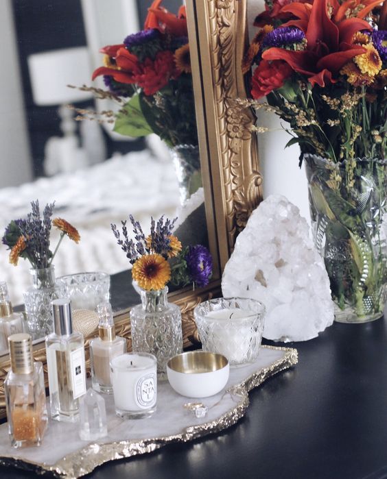 a table topped with vases filled with flowers next to a mirror