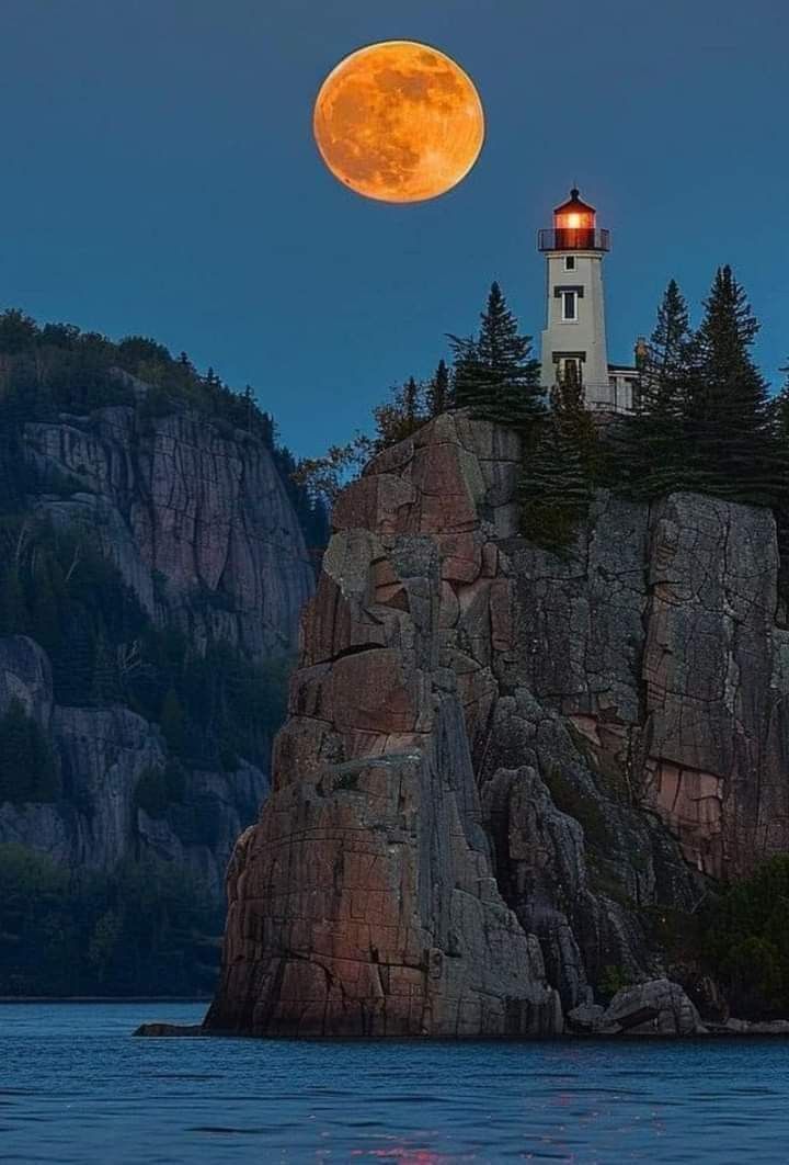 a full moon is seen over a lighthouse on top of a rock outcropping