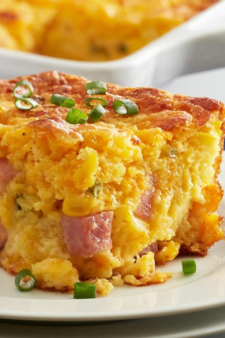 a close up of a piece of food on a plate with green onions and cheese