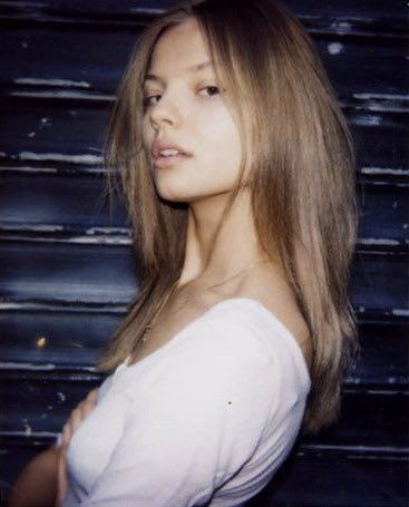 a woman with long hair standing in front of a wall