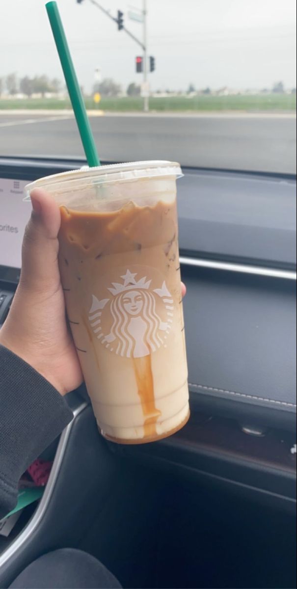 a person holding up a starbucks drink in their car