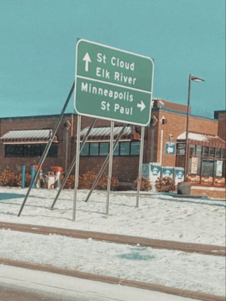 a street sign sitting on the side of a road next to a snow covered field