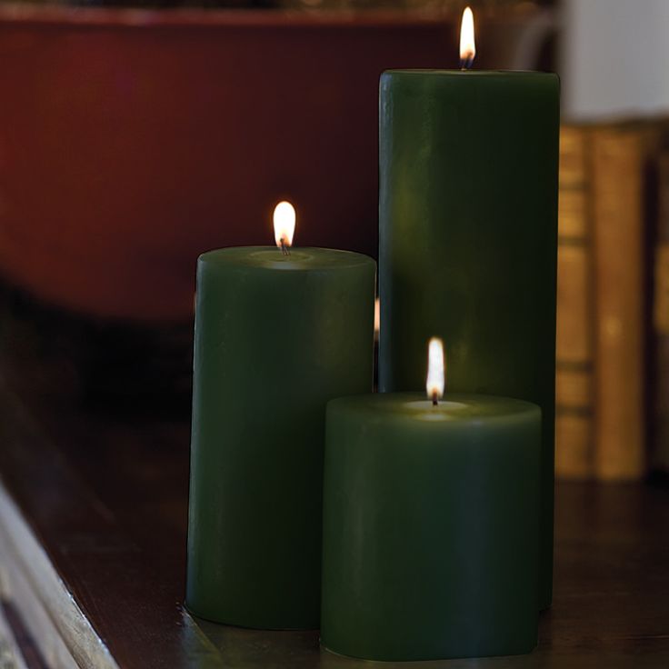 three green candles sitting on top of a table