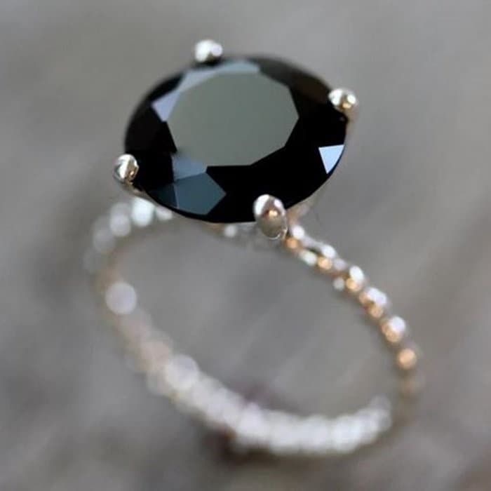 a black diamond ring sitting on top of a wooden table