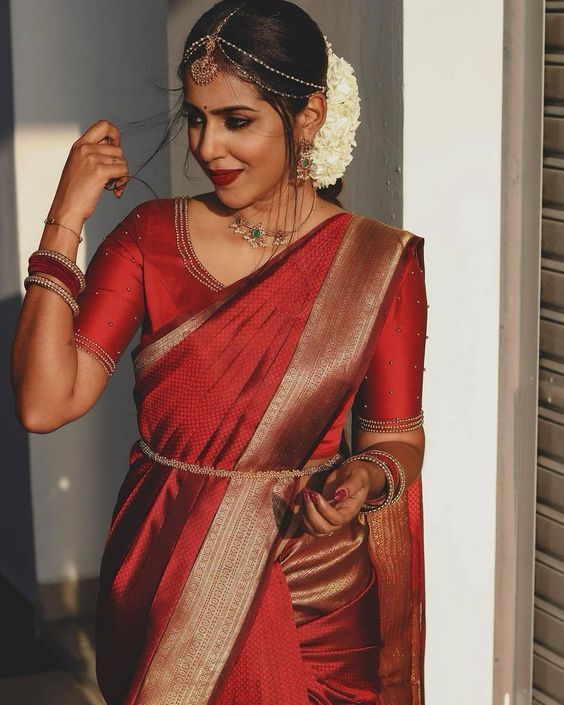 a woman in a red and gold sari is posing with her hand on her hip