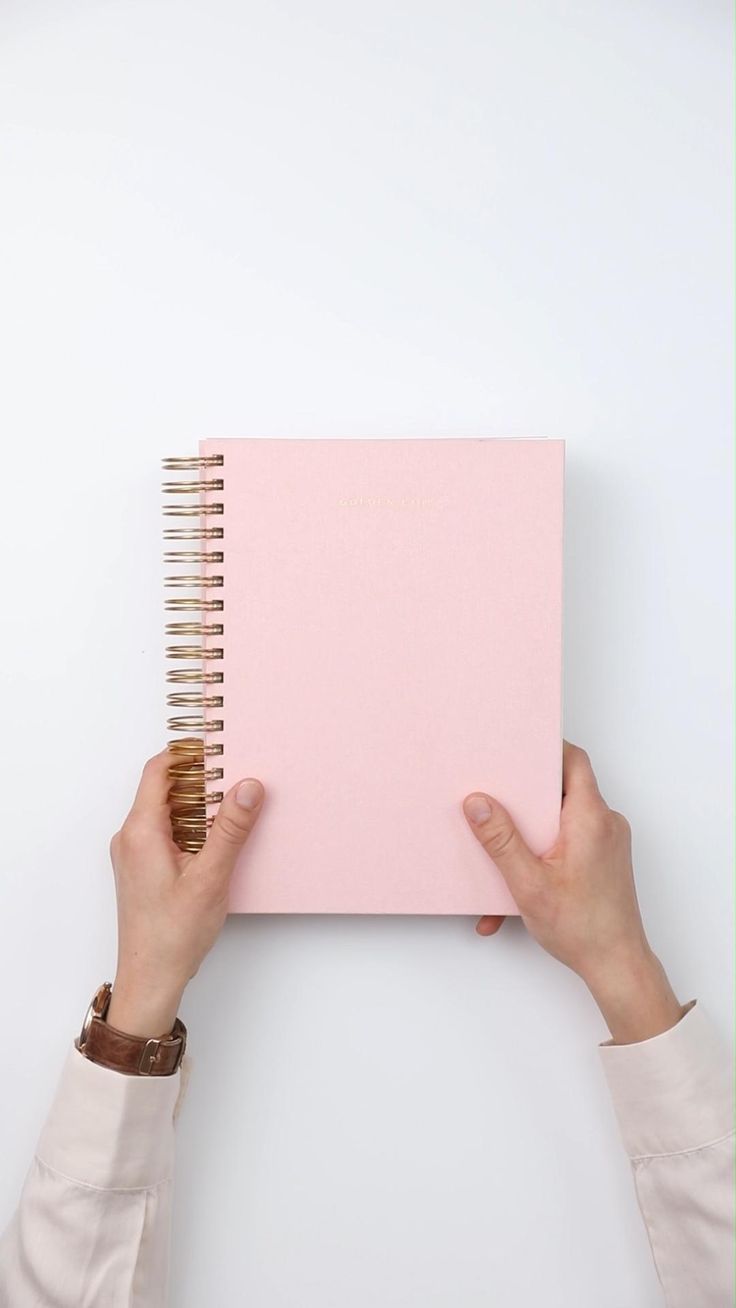 a person holding a pink notebook in their hands