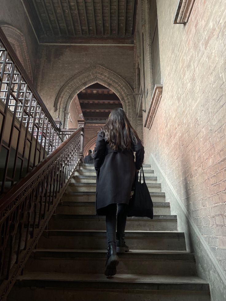 a woman walking up some stairs with a handbag