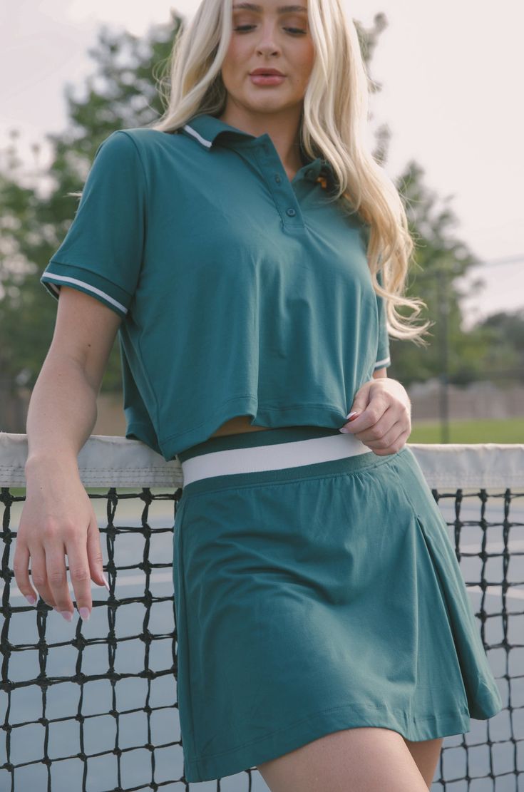 Our Courtside Green Tennis Polo Shirt is perfect for an athletic look. Constructed from butter-soft fabric, this crop-length shirt features a classic polo-style collar. Match it with the Courtside Green Tennis Mini Skirt for the perfect outfit on or off the court. butter soft green tennis polo shirt cropped relaxed loose fit 84% poly microfiber 16% spandex machine wash cold model is wearing a small Sporty Polo Collar Top For Summer, Casual Stretch Polo Shirt For Sports, Relaxed Fit Collared Sports Top, Sporty Polo Shirt For Spring Sports, Sporty Spring Polo Shirt For Sports, Sporty Relaxed Fit Polo Shirt For Sports, Preppy Fitted Top With Polo Collar, Relaxed Fit Polo Collar Sports Tops, Relaxed Fit Sports Tops With Polo Collar