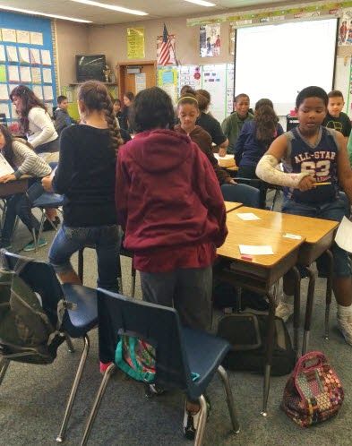 a group of students sitting at desks in a classroom with their backs to the camera