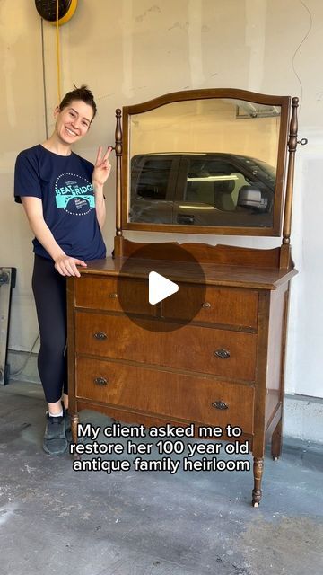 a woman standing next to a wooden dresser with a mirror on it's top