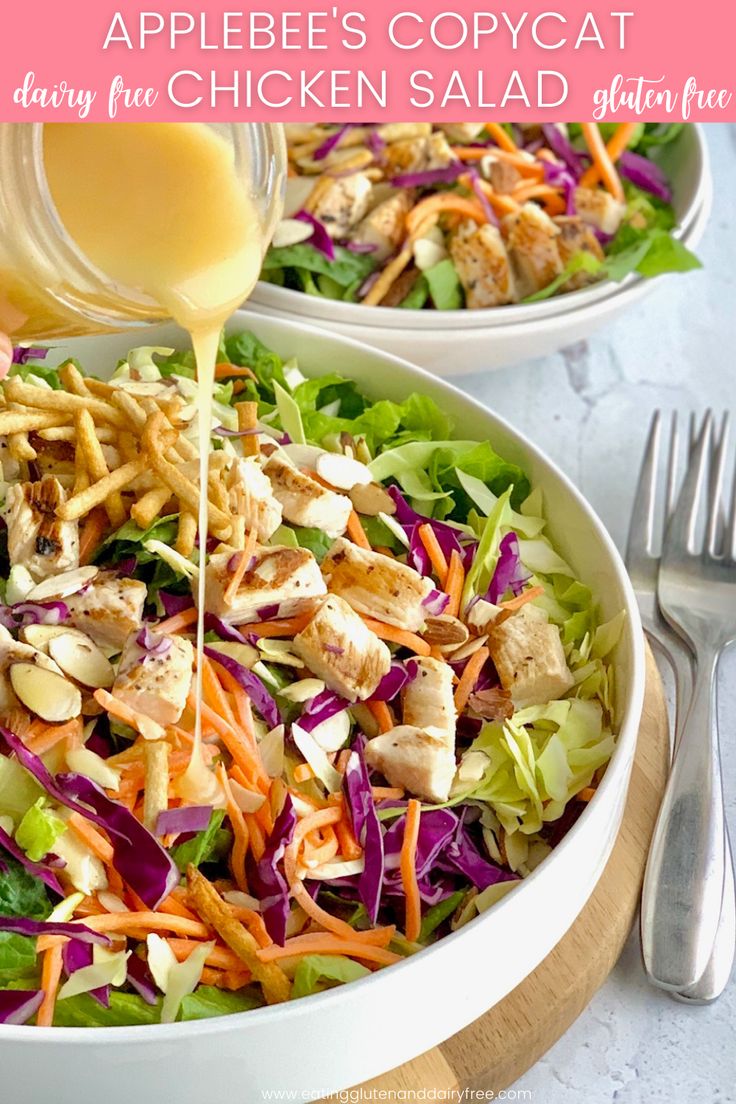 a salad with dressing being poured onto it and topped with chicken, lettuce, carrots, and croutons