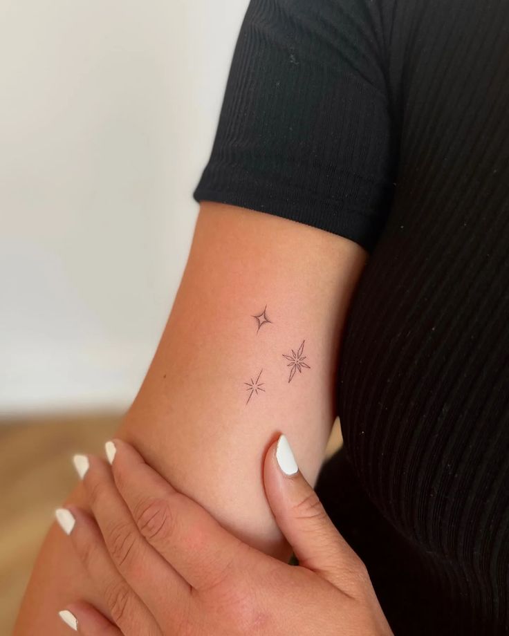 a woman's arm with stars on it and her hand holding the wrist tattoo