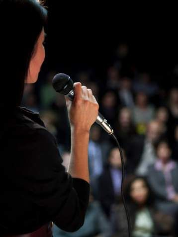 a woman holding a microphone in front of an audience