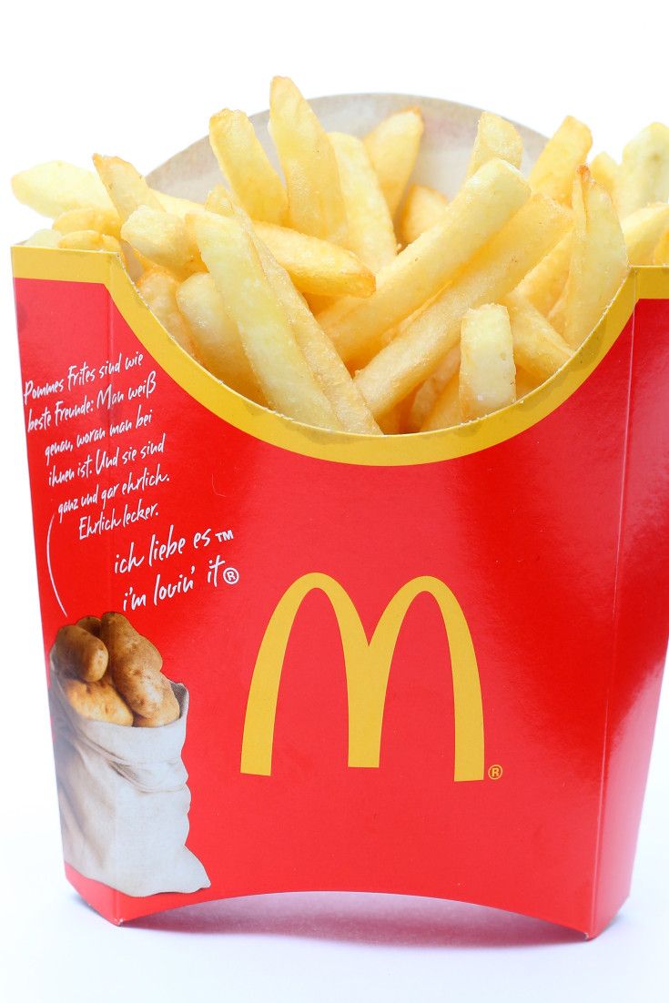 a red box filled with french fries on top of a white table