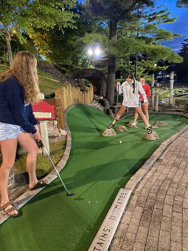 three people playing mini golf at the miniature golf course