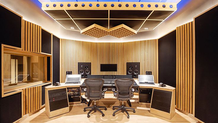 an empty recording studio with multiple monitors and sound equipment on the walls, along with two desks