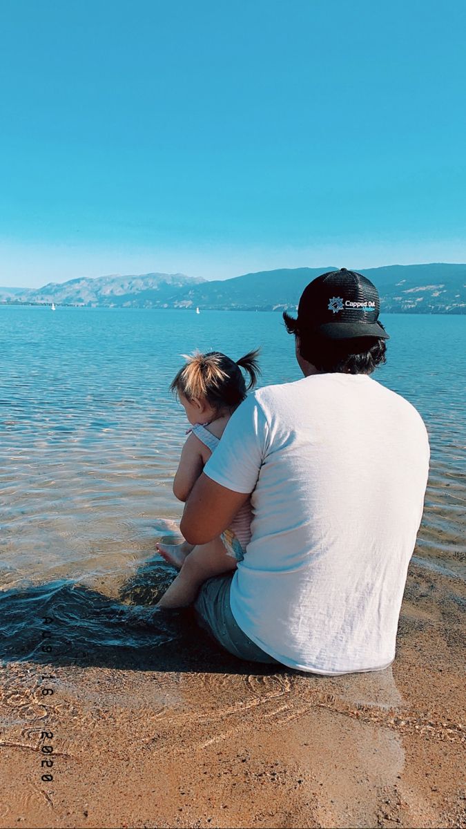 a man and child sitting on the beach