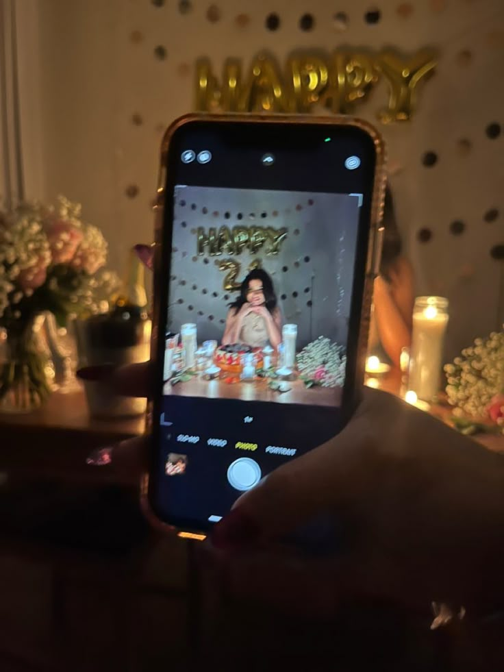 someone is holding up their cell phone to take a photo with her birthday cake on it