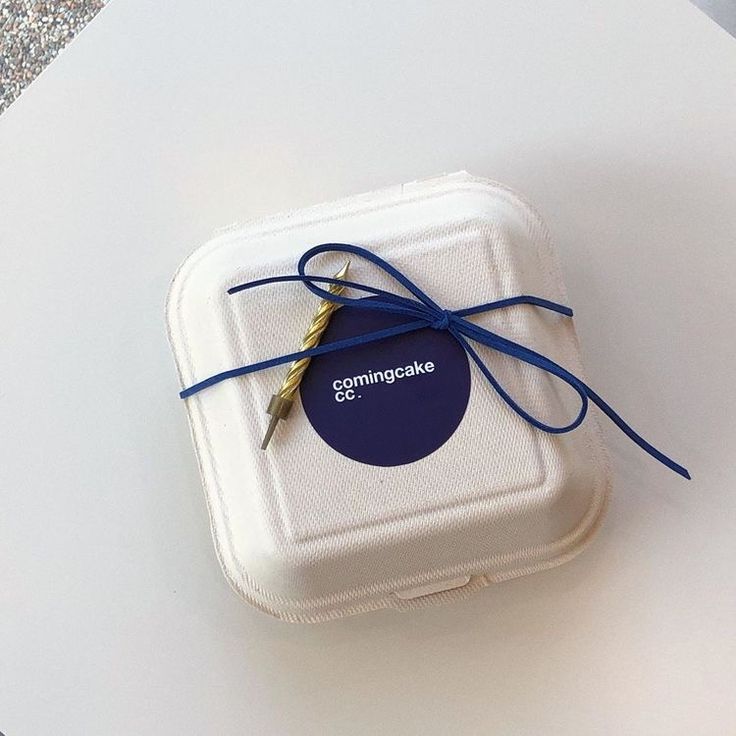 a white box with a blue ribbon tied around it on a counter top next to scissors