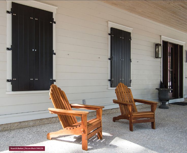 two wooden chairs sitting in front of a white building