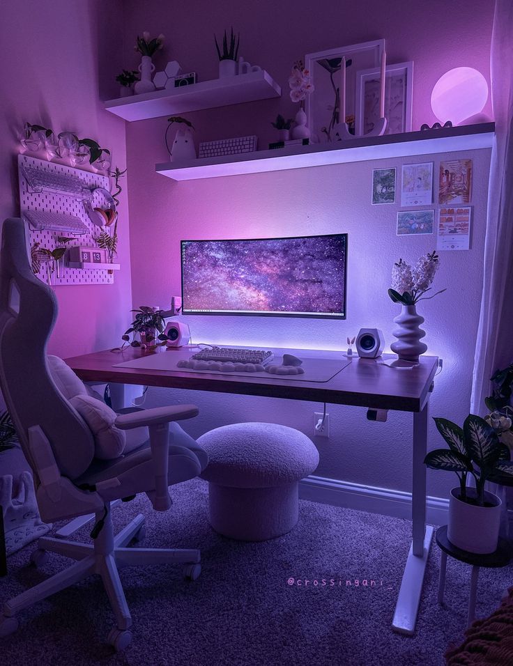 a desk with a computer on it in front of a purple wall and some potted plants