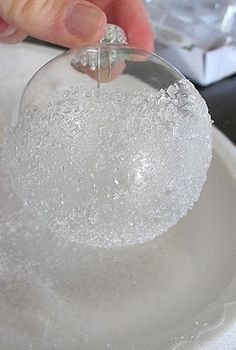 a person is holding an ornament on a plate with snow flakes around it