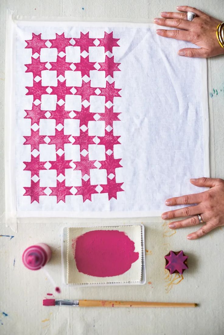 someone is making a quilt with pink and white stars on the fabric, next to some crafting supplies