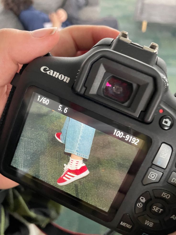 a person holding up a camera to take a photo with their feet on the ground