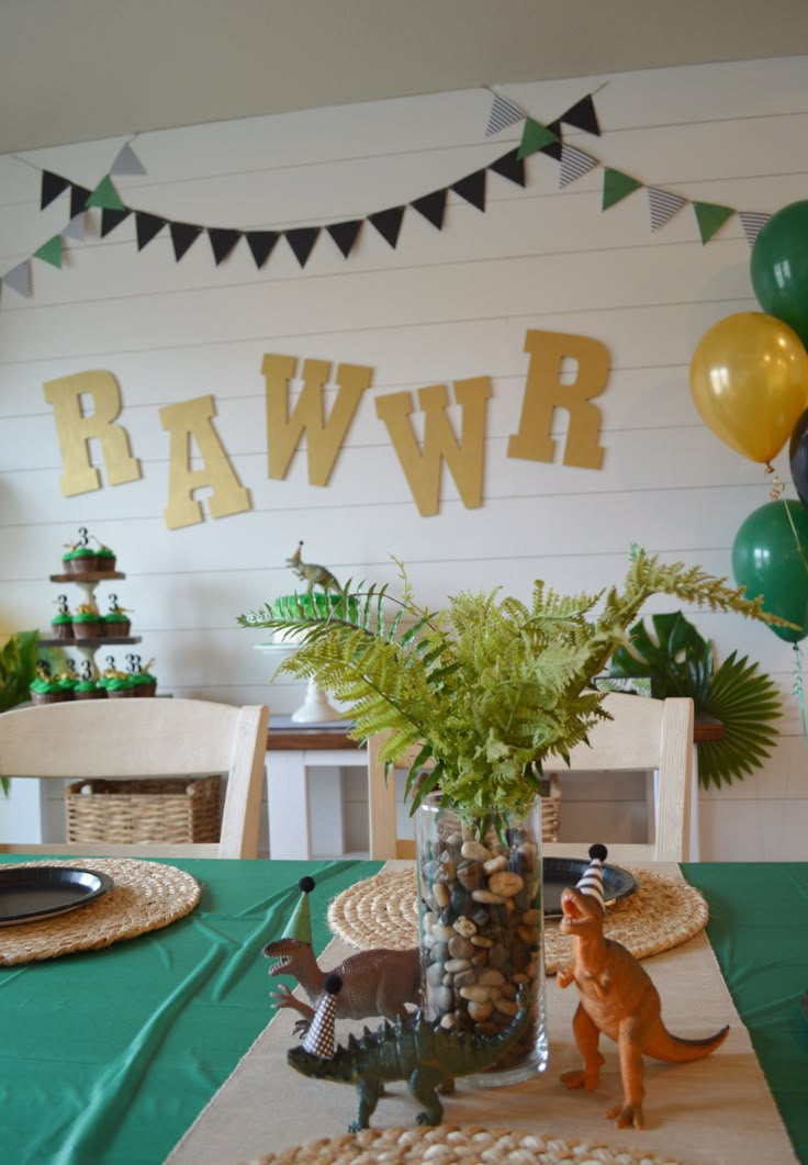 a table topped with a vase filled with plants and animals next to a sign that says rawr